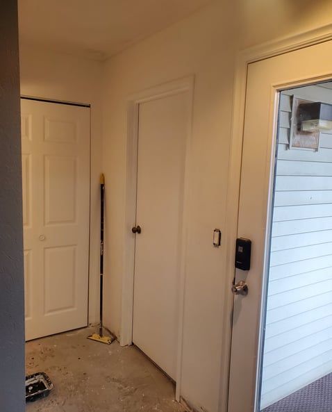 A hallway with a door and a mop on the floor