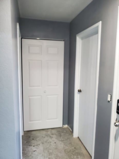 A hallway with a white door and gray walls.