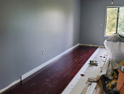 A room with hardwood floors and gray walls is being remodeled.