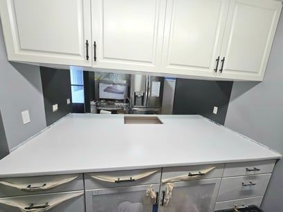 A kitchen with white cabinets , a sink , and a refrigerator.