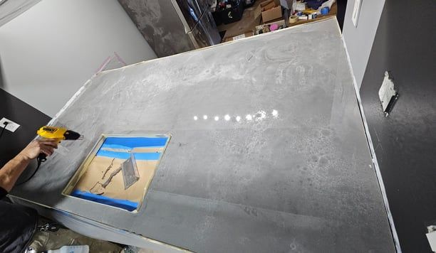 A person is using a drill on a concrete surface.