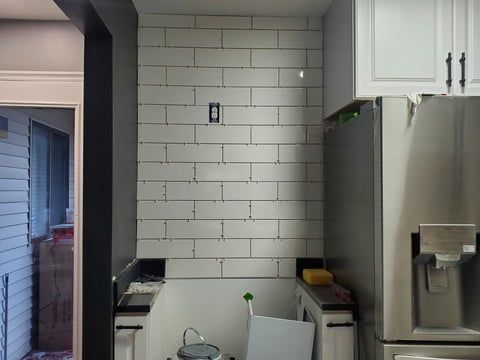 A kitchen with white cabinets and a stainless steel refrigerator