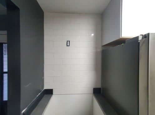 A bathroom with white tiles and a black wall.