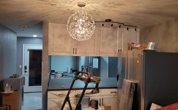 A kitchen with a ladder and a chandelier hanging from the ceiling.