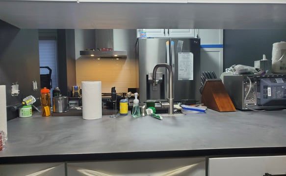 A kitchen counter with a sink and a refrigerator.