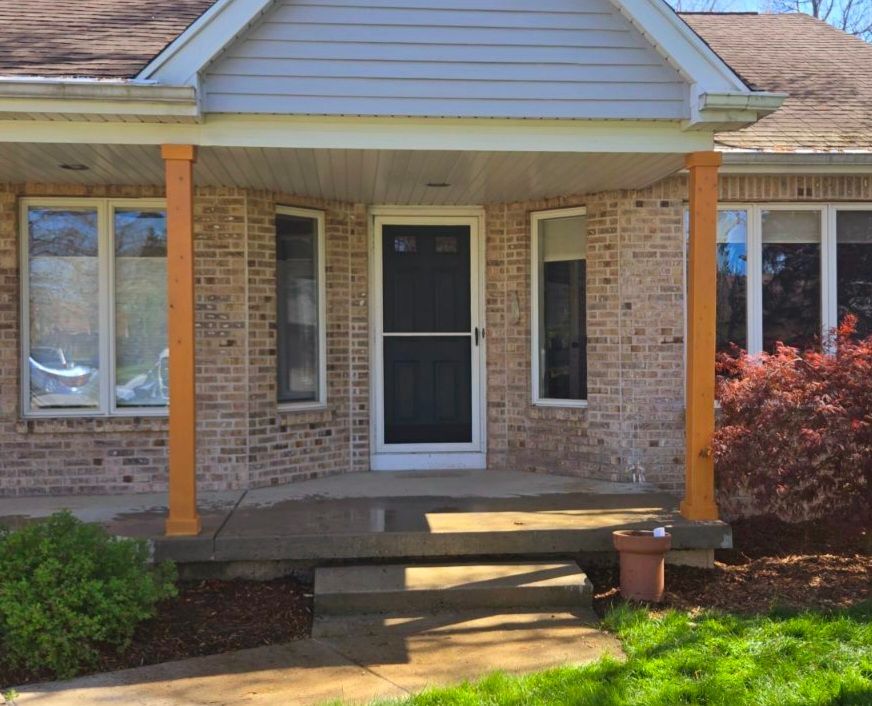 The front porch of a brick house with a screen door
