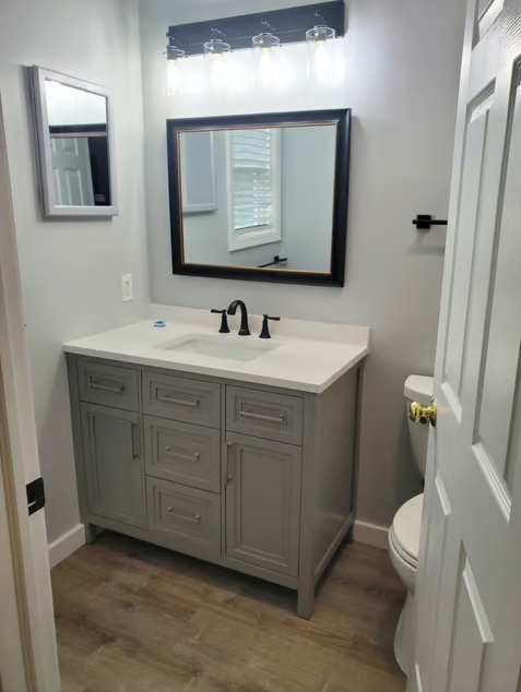 A bathroom with a sink , mirror and toilet.