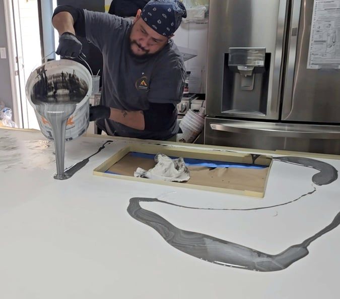 A man is pouring paint into a bucket on a counter