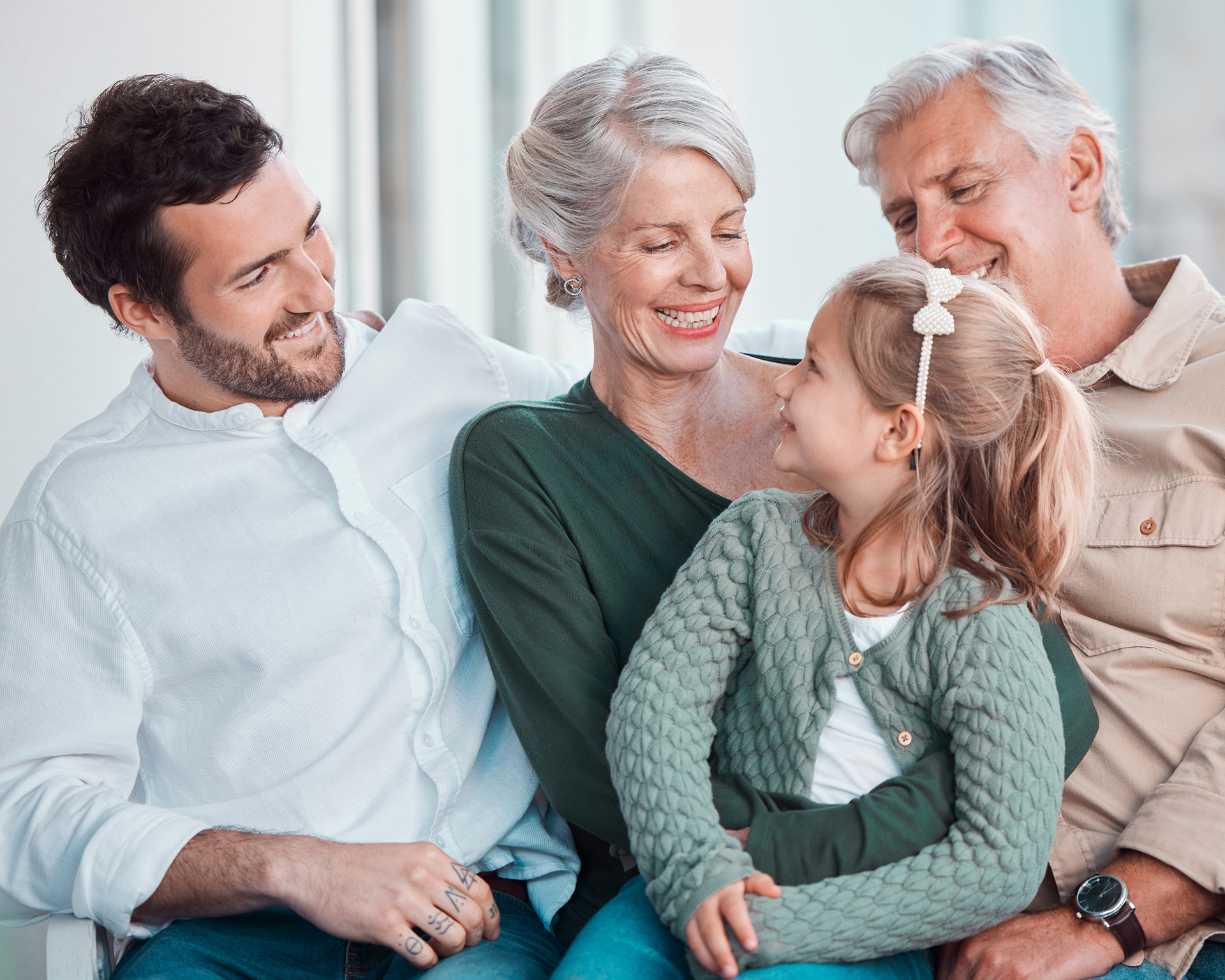Family of four: A smiling girl looks at her grandma, with dad and grandpa nearby.
