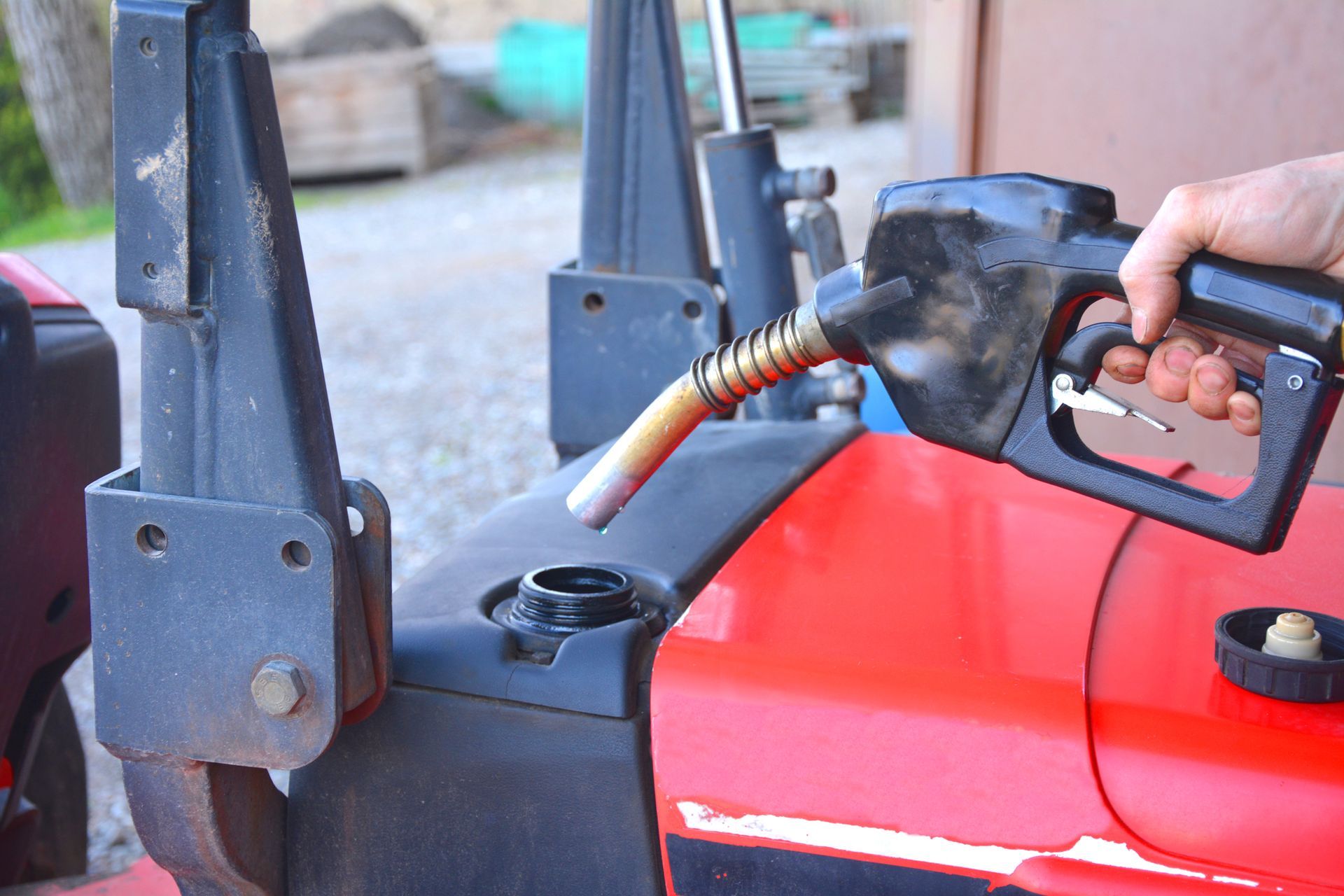 Worker refuels red tractor, keeping farm machinery running.