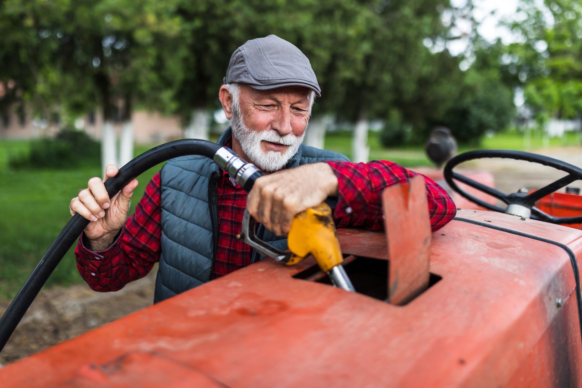 Farmer fueling tractor with yellow nozzle outdoors. Farmer fueling tractor with yellow nozzle outdoors.