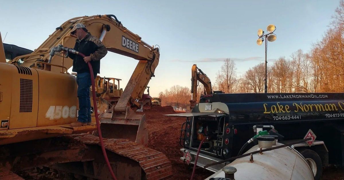 A man in red overalls is standing next to a red tractor.