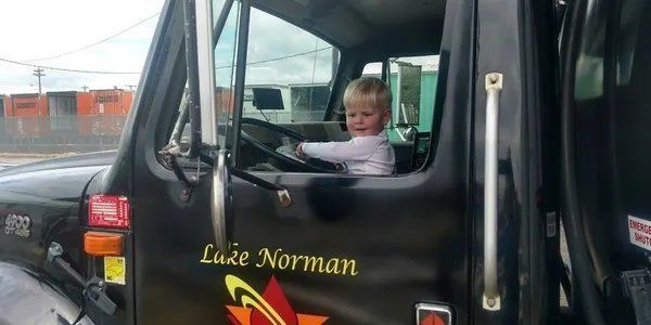 A little boy is sitting in the driver 's seat of a truck.