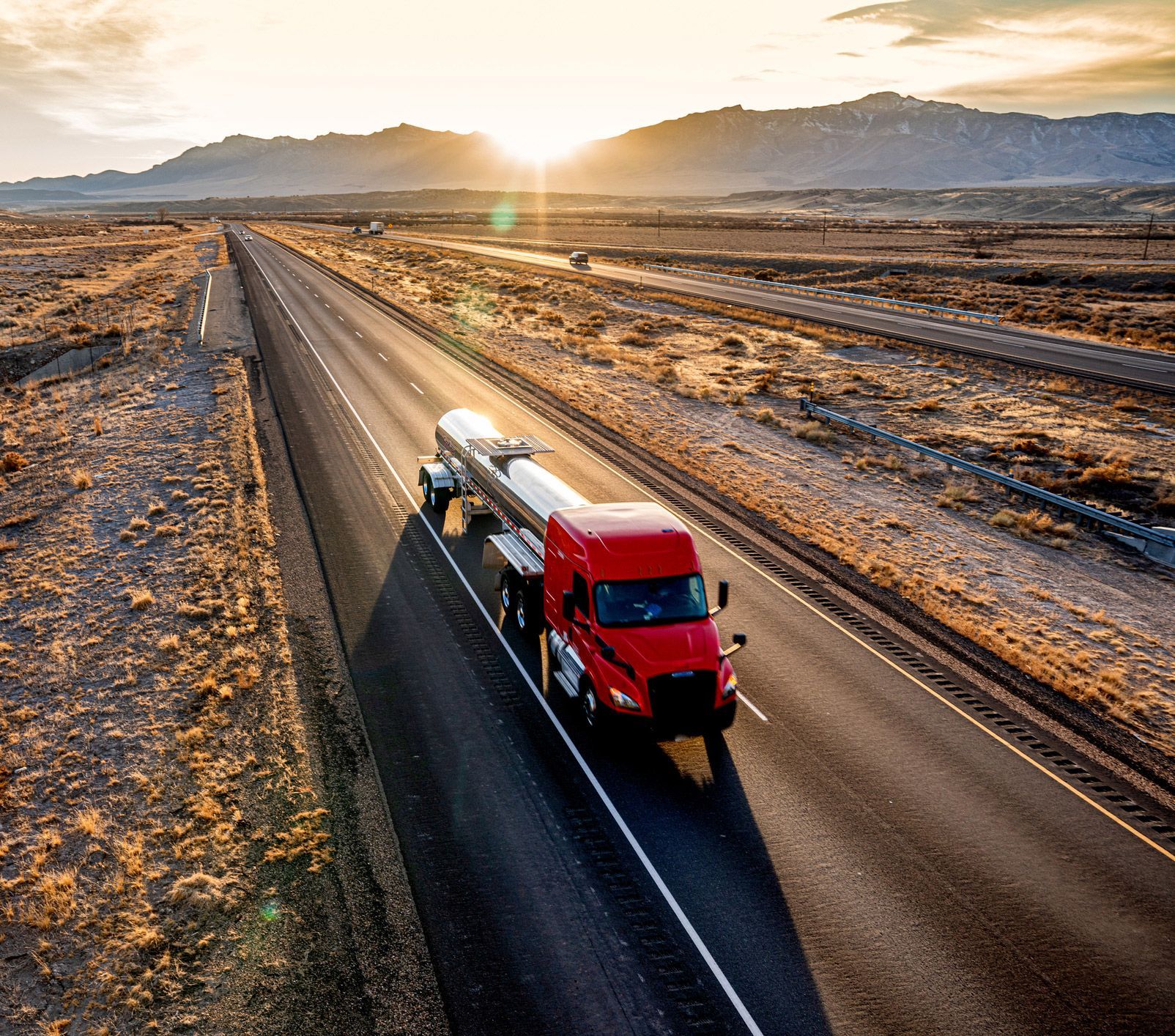An aerial view of a red semi truck driving down a highway.