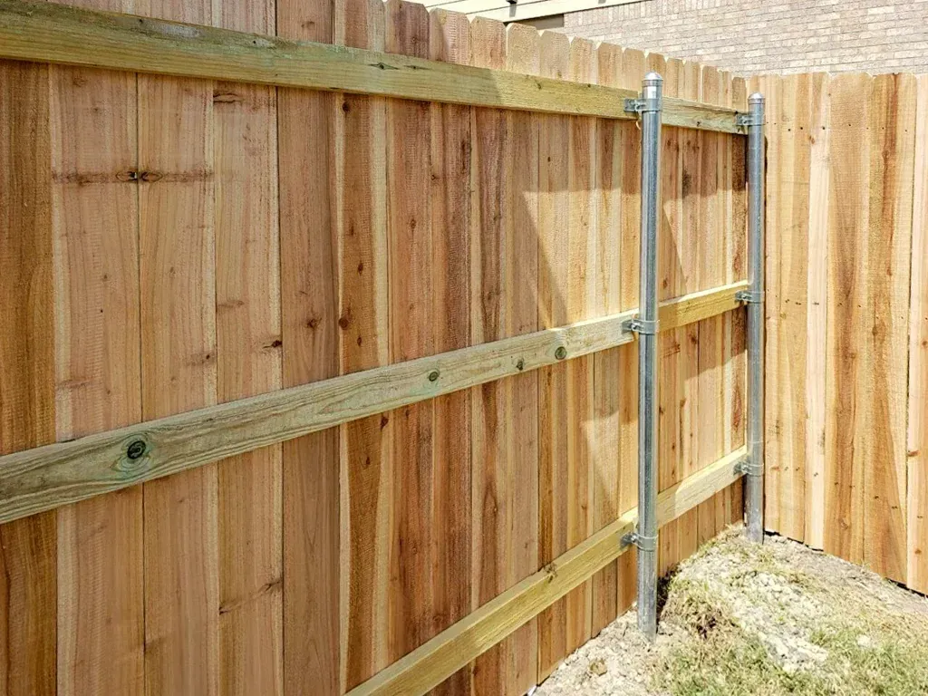 Wooden privacy fence with vertical boards and horizontal supports, metal posts visible.