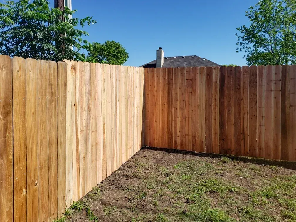 Wooden fence in a backyard, corner view, on a sunny day.
