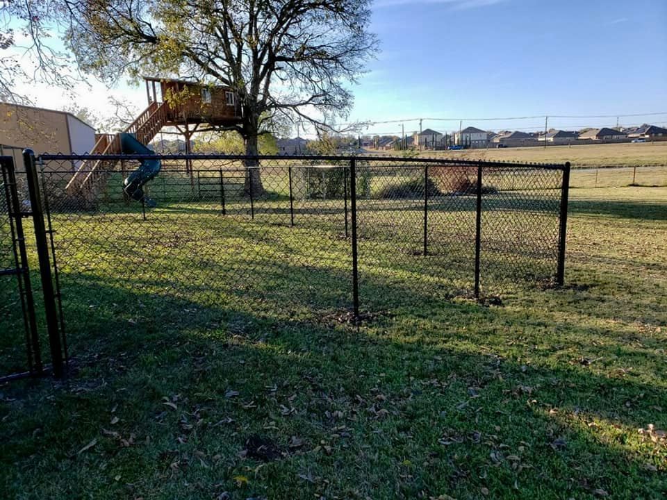 A chain link fence surrounds a playground with a slide.