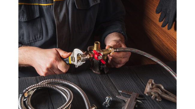 A man is fixing a faucet with a wrench.