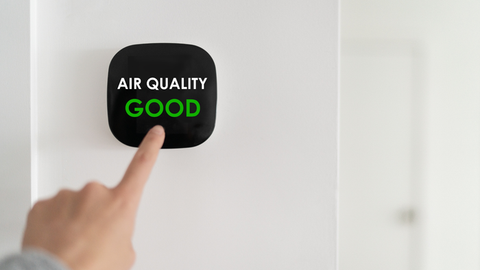 A person is pressing a button on a wall that says `` air quality good ''.