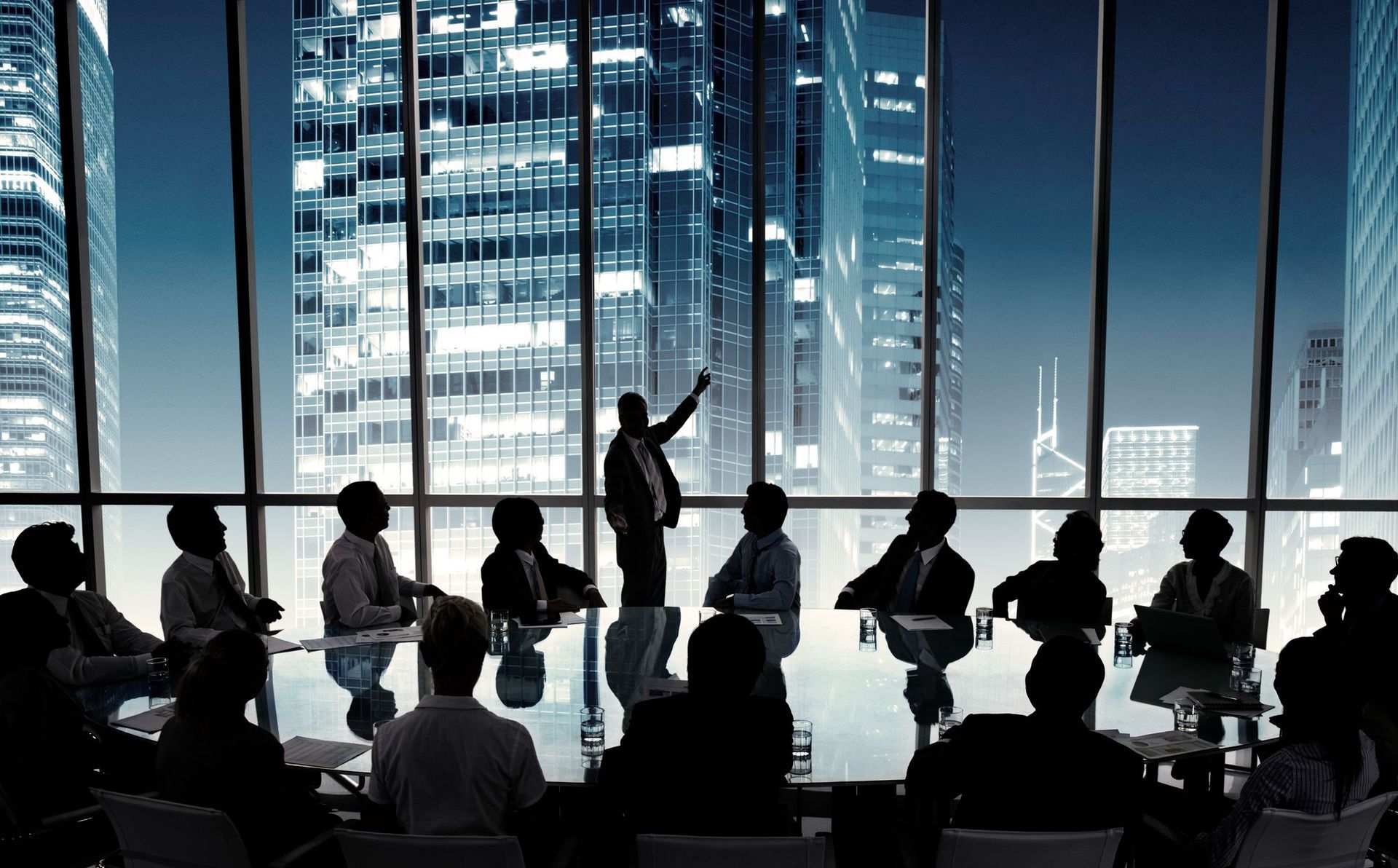 Silhouetted meeting in a glass-walled office with a city skyline at night