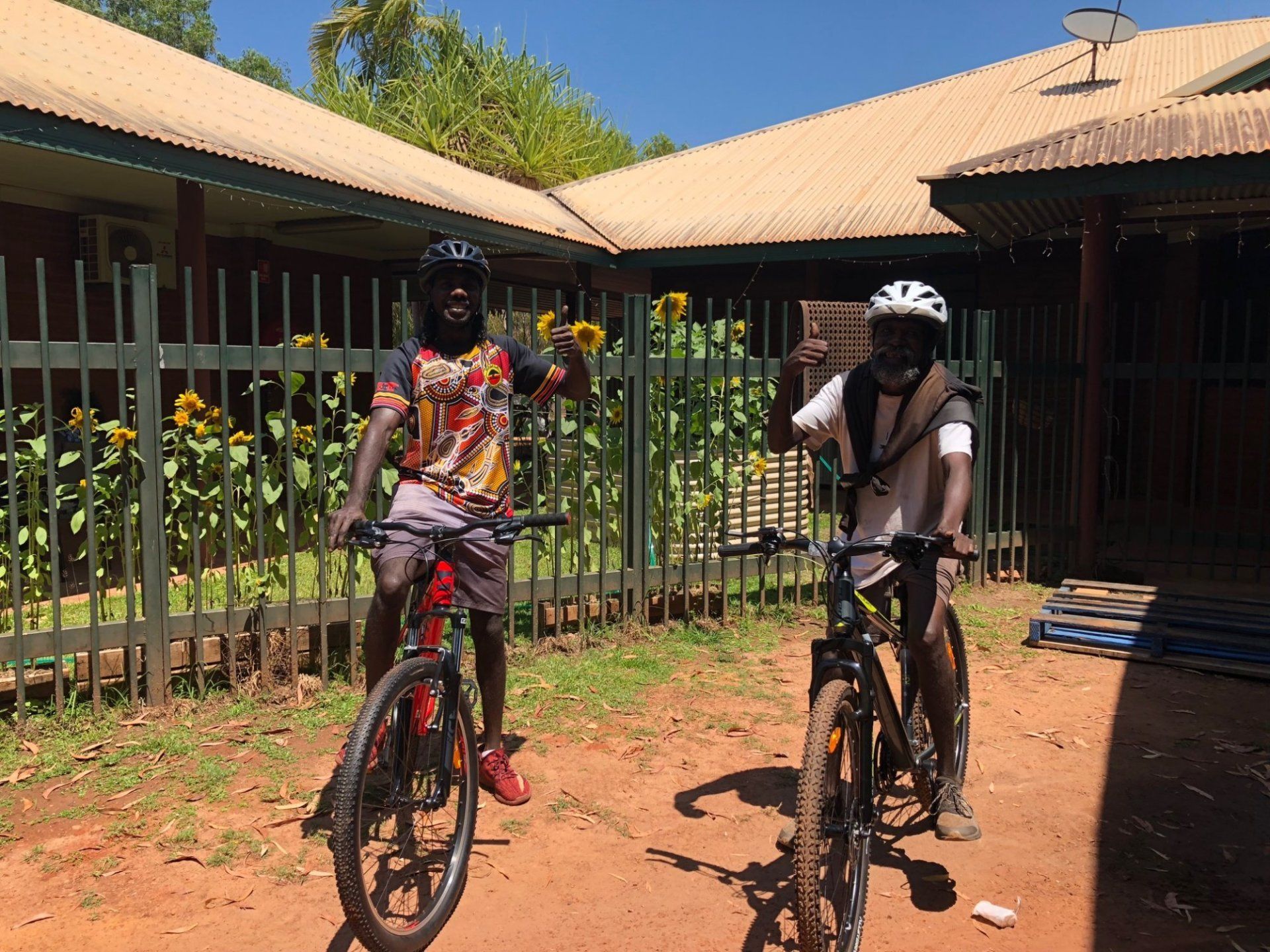 Two men are riding bicycles in front of a building
