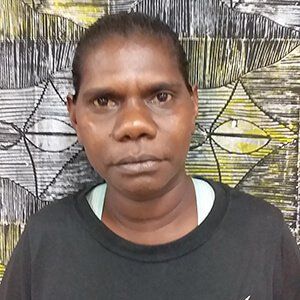 A woman in a black shirt is standing in front of a painting.