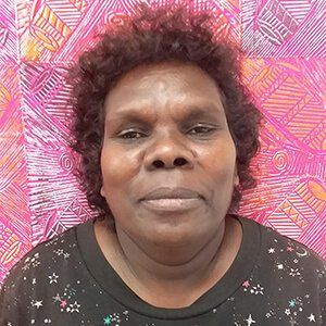 A woman with curly hair is standing in front of a colorful wall.