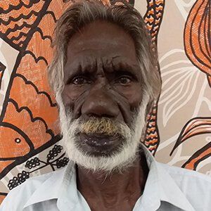A man with a beard and mustache is standing in front of a painting.