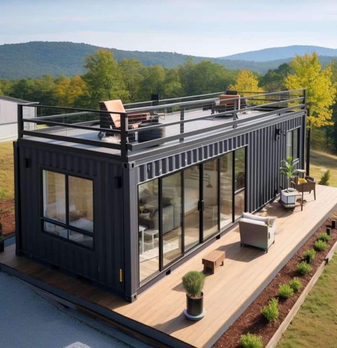 Moderna casa contenedor negra con terraza en la azotea con vista a un pintoresco paisaje montañoso.