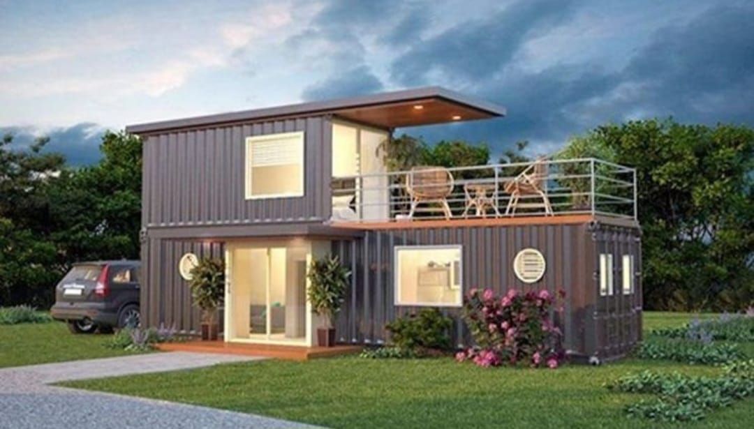 Casa contenedor de dos plantas con balcón. Exterior gris oscuro, césped, coche y cielo nublado.