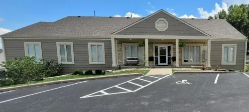 A one-story building with a covered entrance, a wheelchair-accessible parking space, and a blue sky.
