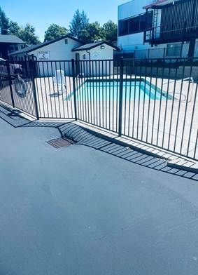 There is a swimming pool behind a metal fence.