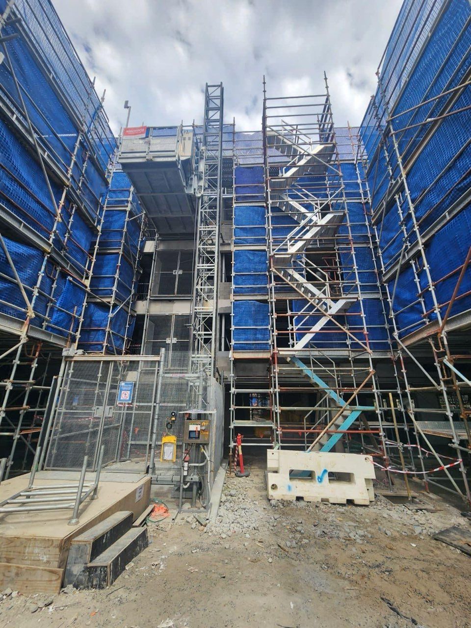 Scaffolding Surrounds A Building Under Construction, Blue Safety Netting. Stair Access — Big River Scaffolding Solutions Pty Ltd in Coffs Harbour, NSW