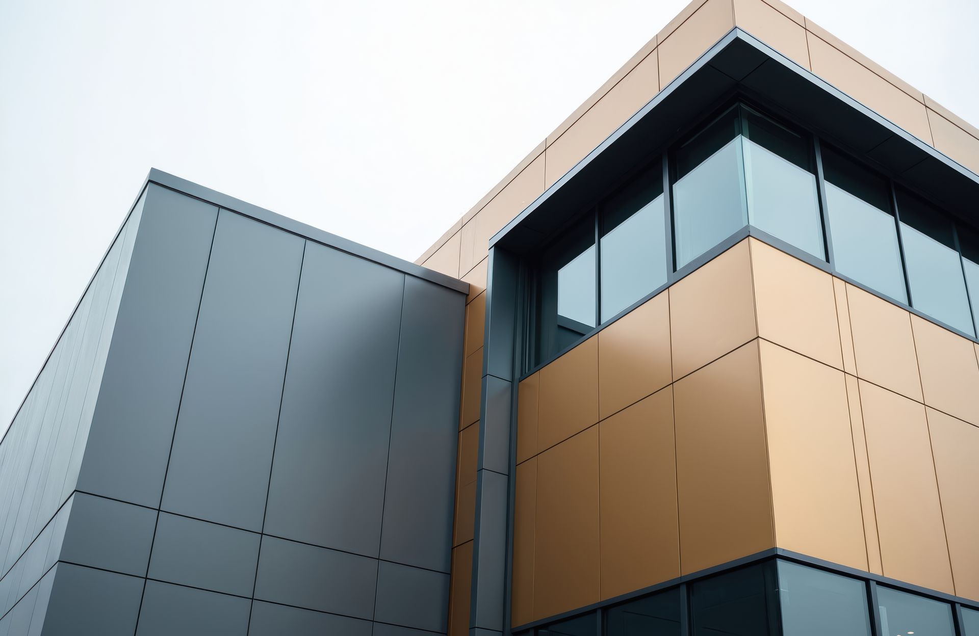 Bottom-up view of a modern building with grey and brown wall cladding outside.