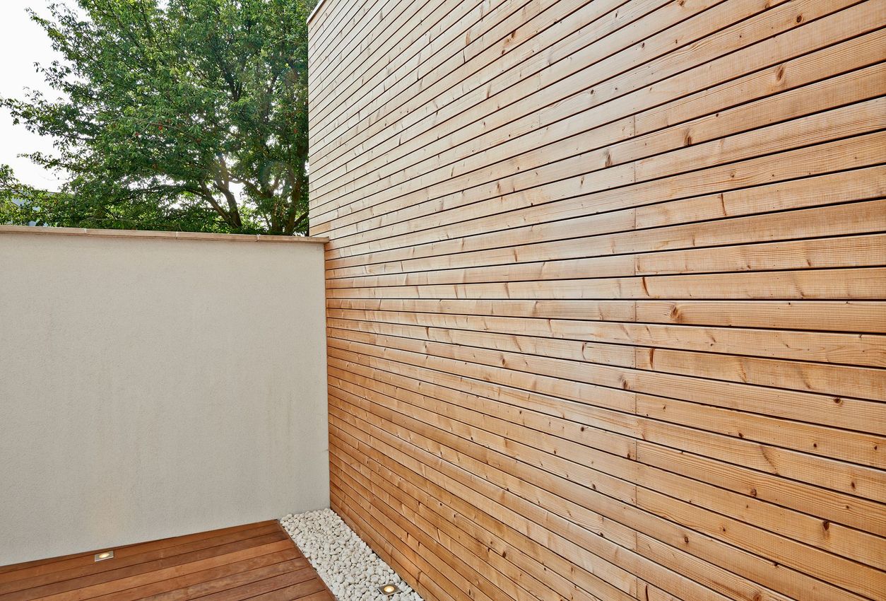 View of a cement wall and insulating wood cladding in an outdoor courtyard.