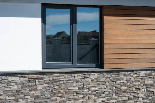 Close-up of a modern wall with stone, wood, and white cladding around a window.