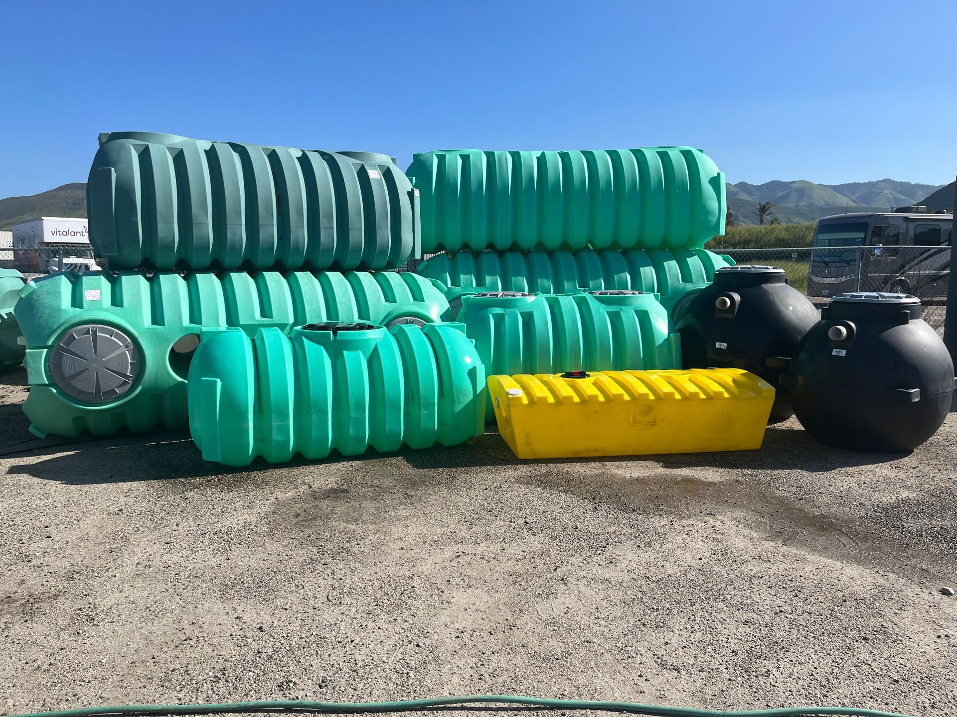A pile of green and black plastic tanks are stacked on top of each other.