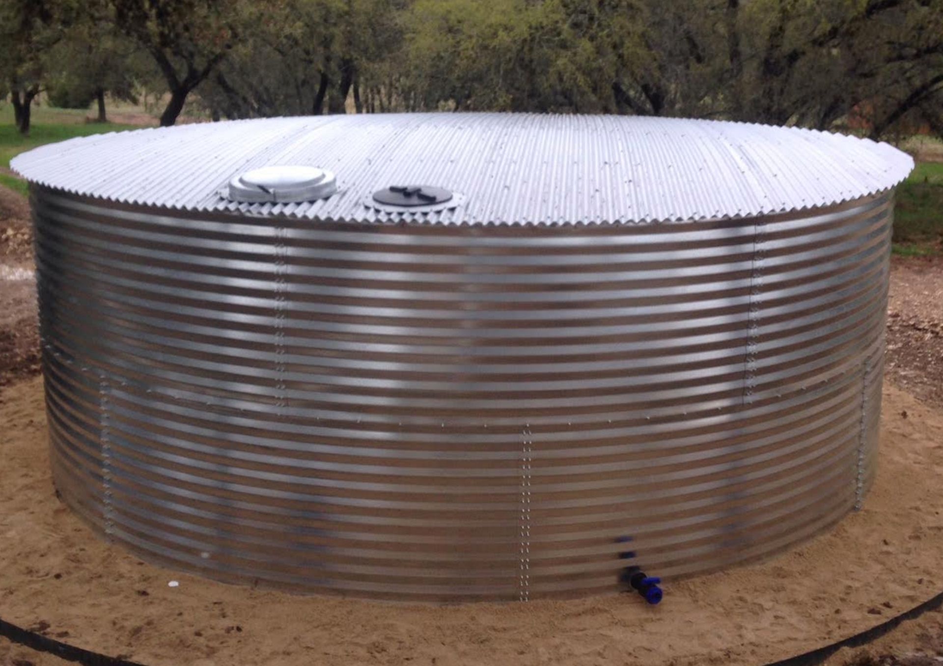 A large metal water tank is sitting in the dirt