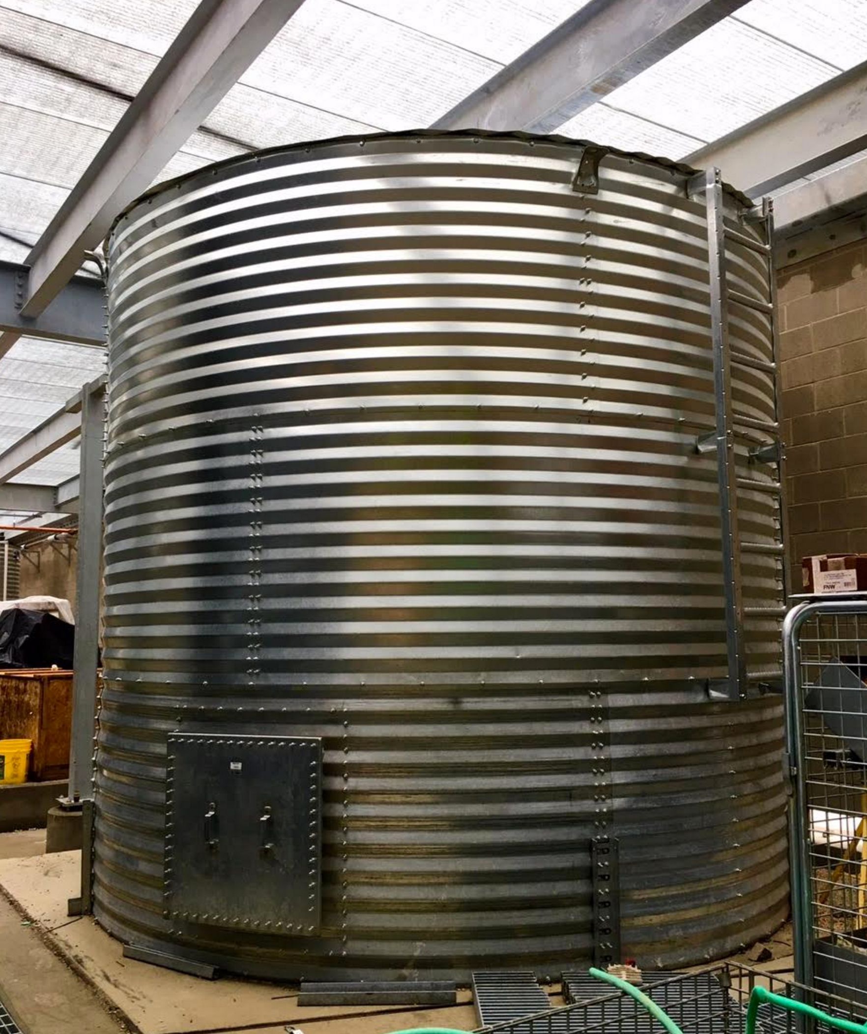 A large metal silo is sitting inside of a building.