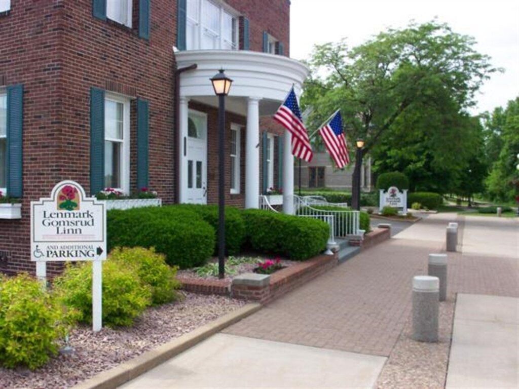 Brick building with white pillars, American flags, and a sign for a Landmark Guesthouse.