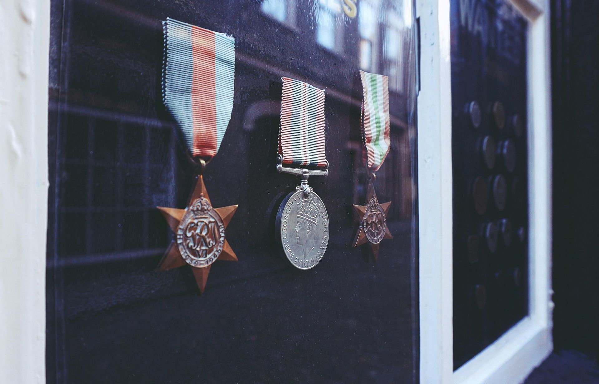 A row of medals hanging on a glass wall.