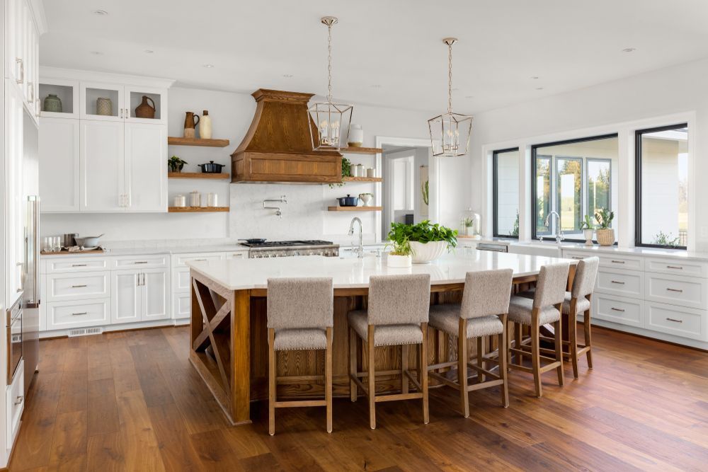 A kitchen with white cabinets , wooden floors , and a large island.