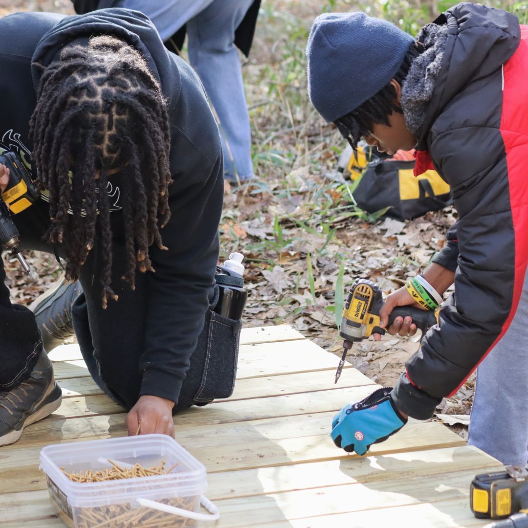 Young men volunteering and building wood structure in nature area