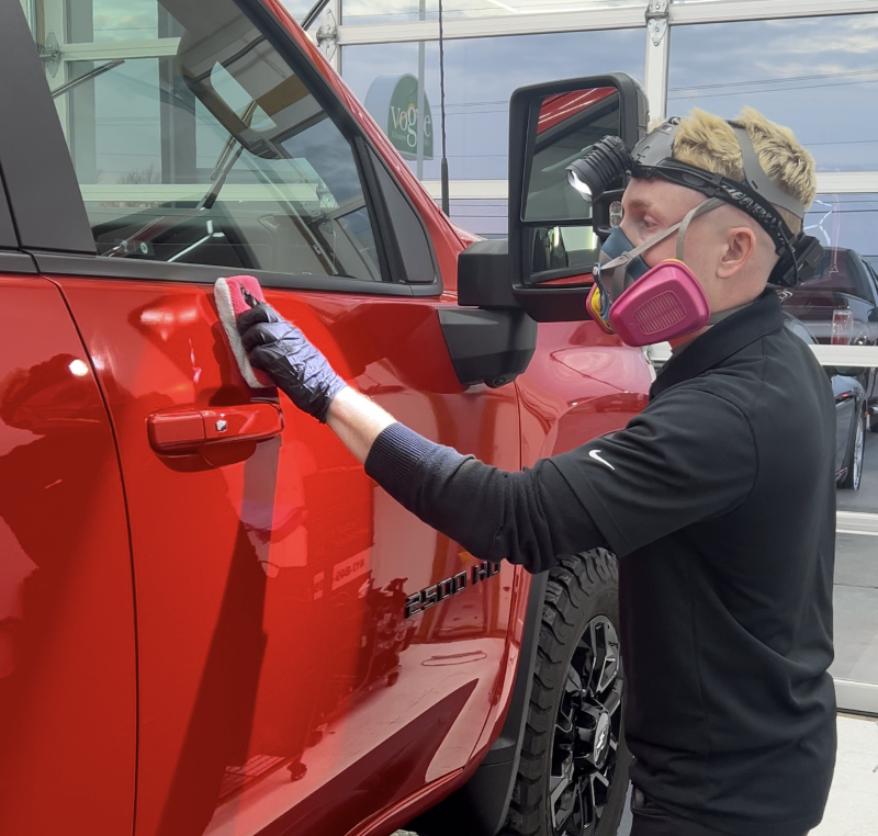 Black GMC truck parked in front of a window tinting shop with a green and blue awning.