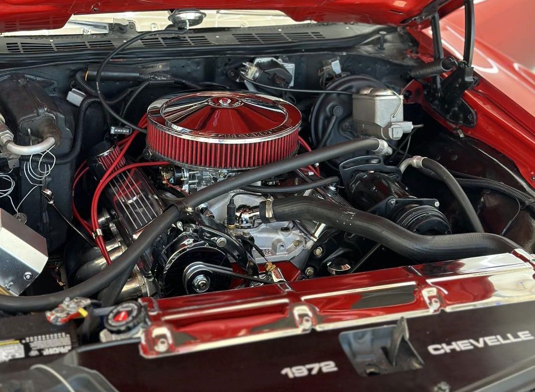 Red classic car engine bay, chrome accents, red air filter, black hoses, 1972 Chevelle.