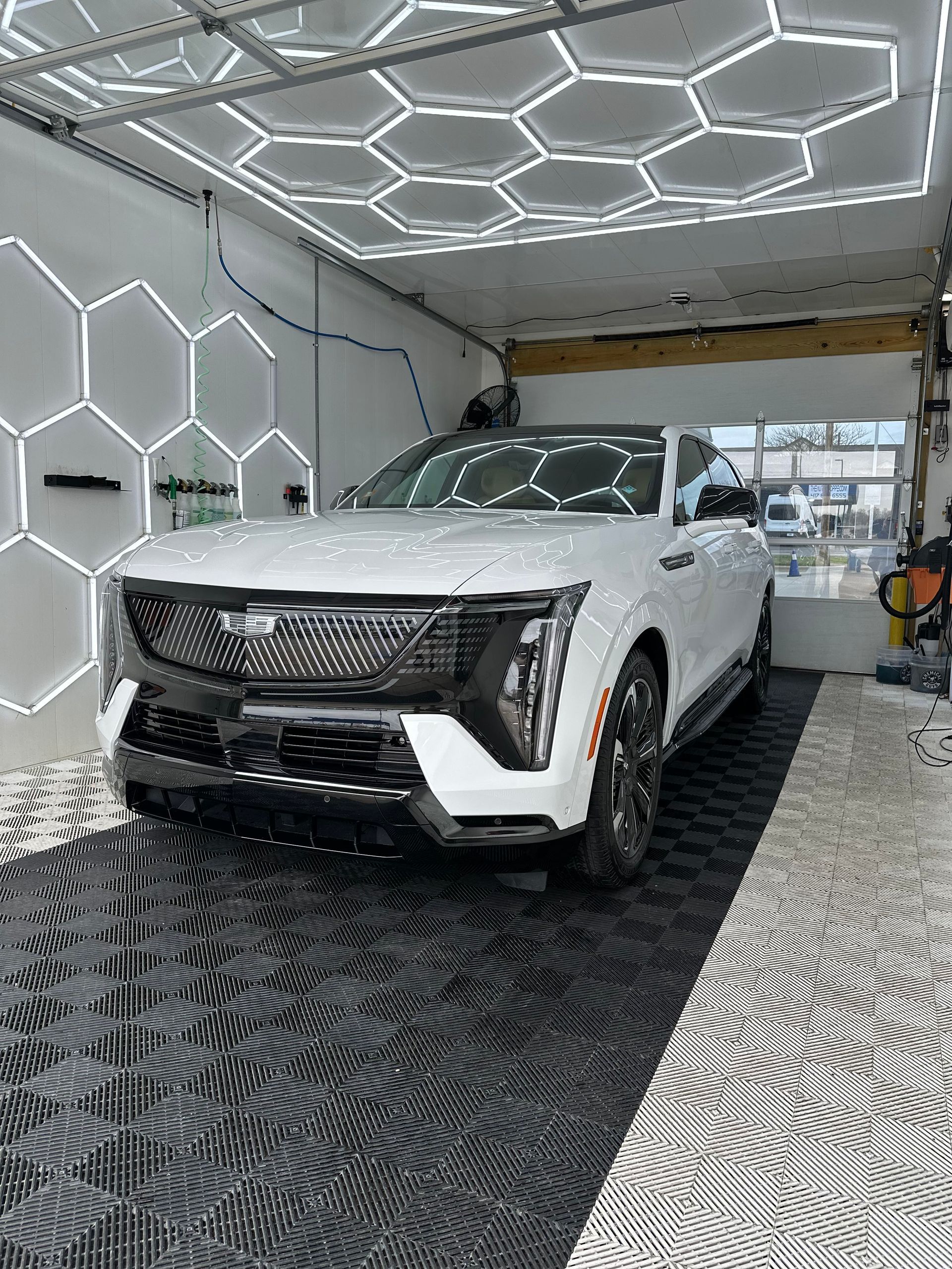 White Cadillac SUV in a garage with honeycomb-shaped lights.