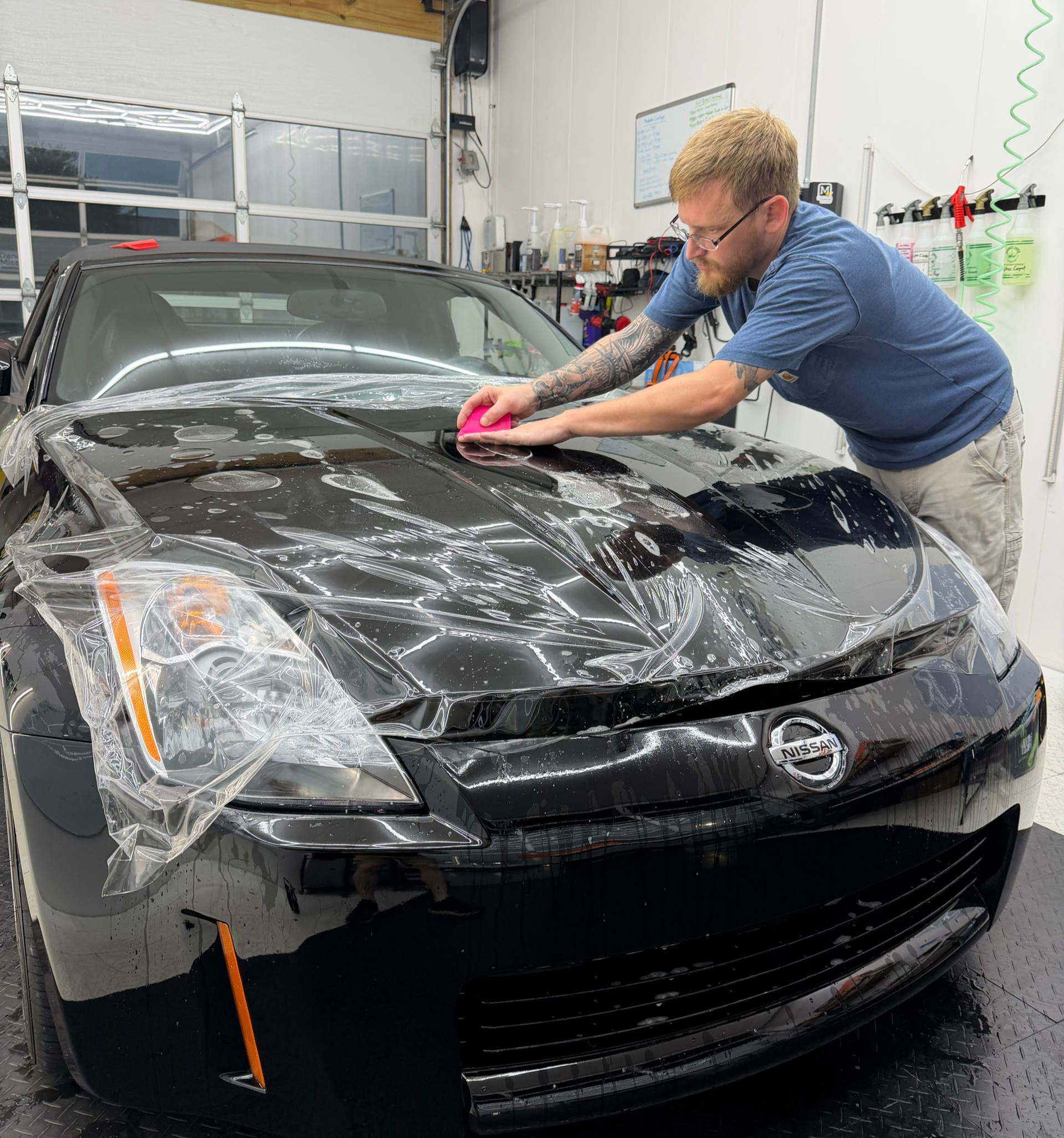 Two people washing a white Mercedes-Benz SUV in front of a brick building.