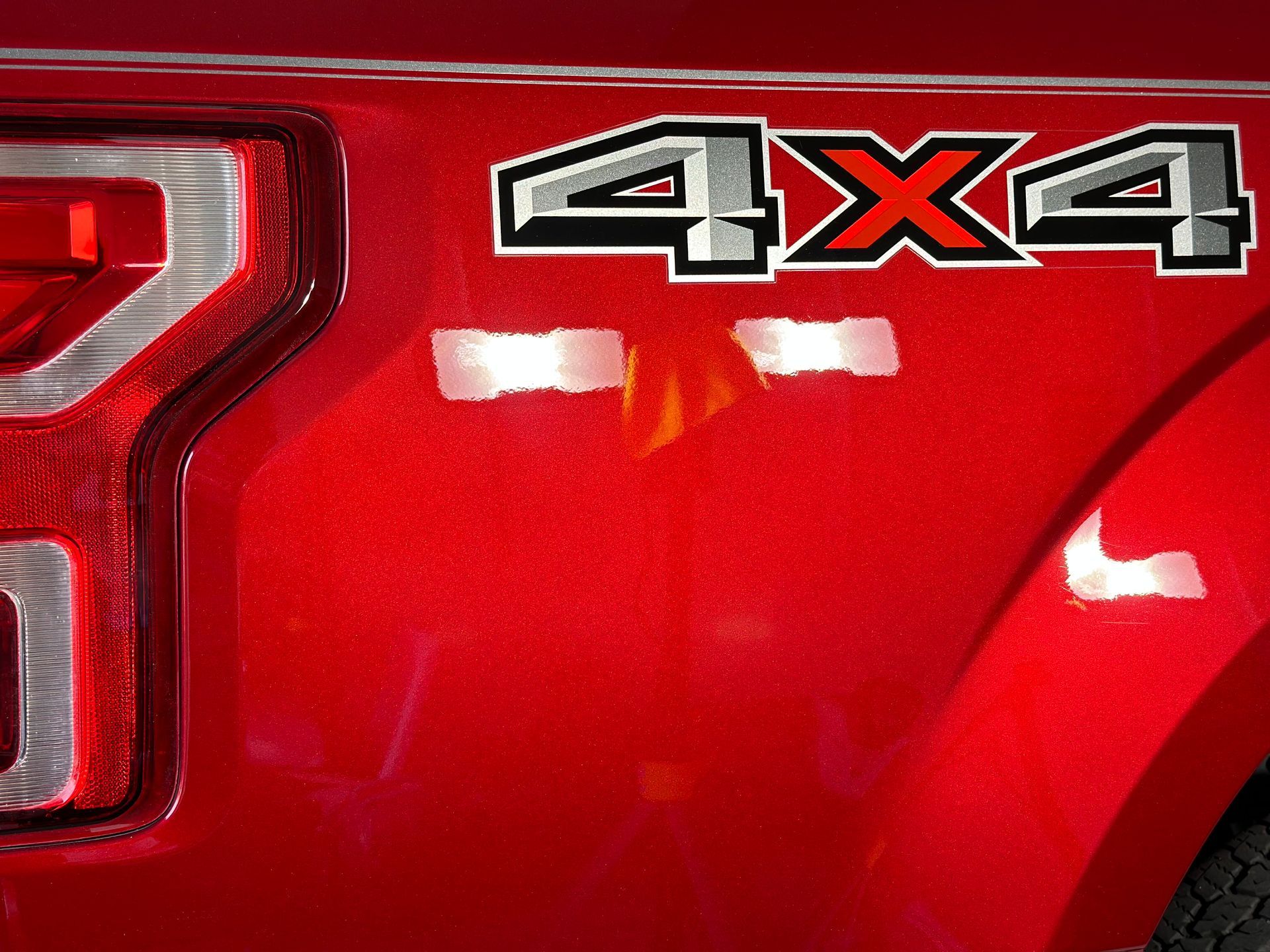 Red pickup truck with a 4x4 decal near the taillight.