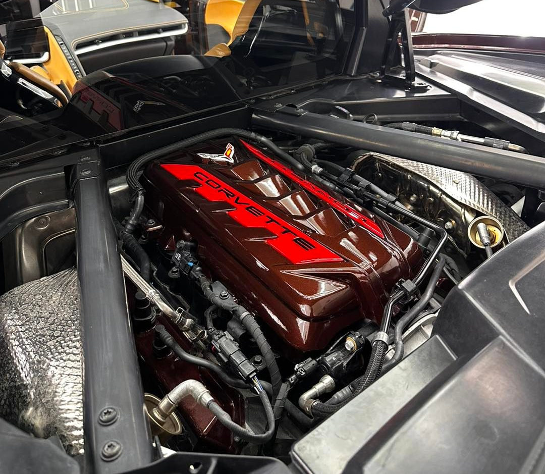 Close-up of a car engine bay, showcasing a red and black engine cover in a sleek black car.