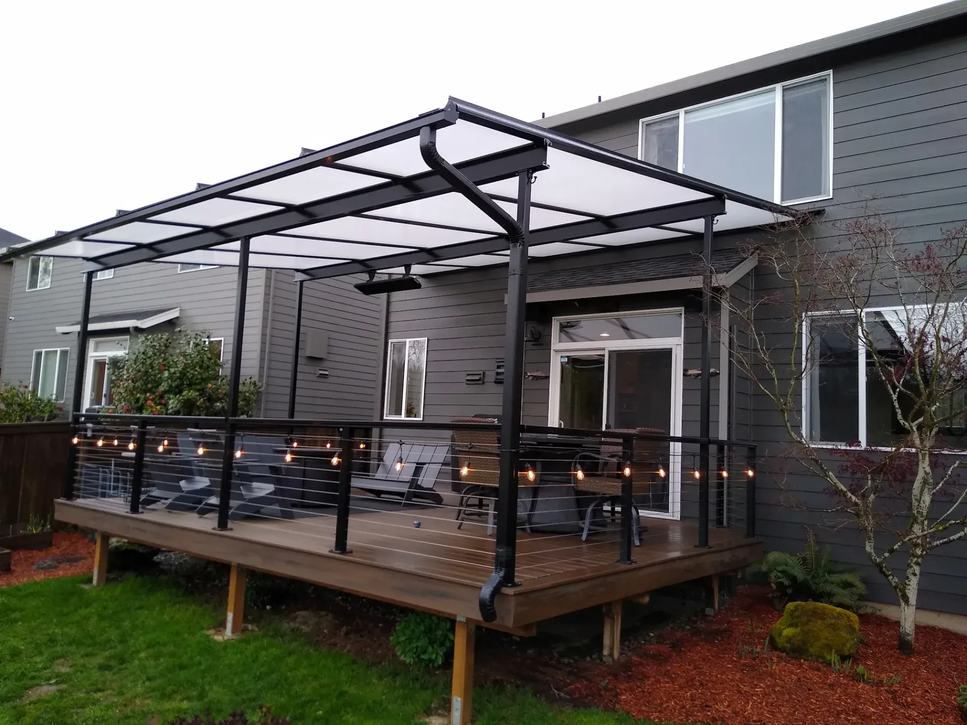 A deck with a canopy over it is in the backyard of a house.